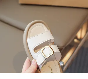 Detail of girls' cream sandals showing leather texture and golden buckle fastener