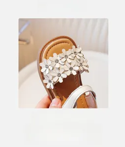 Détail rapproché des sandales fille avec appliques florales blanches et strass étincelants