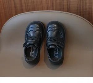 Detailed top view of black leather girl shoes with classic brogue carving and velcro closure
