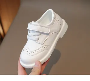 Close-up of girls' white brogue leather shoes with perforated details and velcro strap