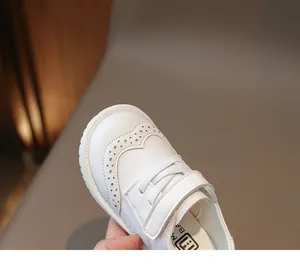 Close-up of white girls' leather shoes with brogue detailing and velcro strap