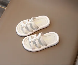 Vista dettagliata di sandali beige per bambina con tre cinturini decorati con perle