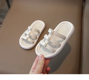 Dettagli di sandali da bambina con tre cinturini ed eleganti perle bianche grandi