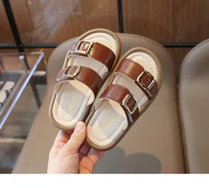 Détail de sandales en cuir marron pour filles avec deux boucles dorées et semelles souples
