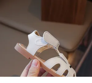 Gros plan de sandales crème pour enfants avec motif lapin ajouré et velcro