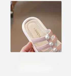 Primo piano di sandali rosa da bambina con cinturini in pelle e grandi accenti di perle bianche