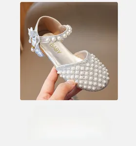Detail von silbernen Mädchen-Prinzessin-Schuhen mit Perlen, Strass und Seidenblumen