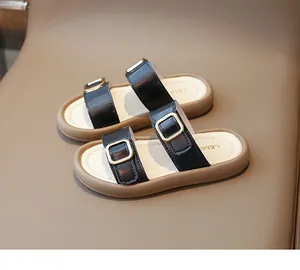 Vue de dessus de sandales pour filles en cuir noir avec boucles dorées et semelles brunes