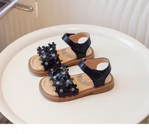 Détail de sandales noires pour filles avec fleurs 3D et ornements en strass brillants