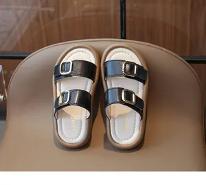 Gros plan de sandales noires à plateforme pour filles avec boucles dorées et logo Lemon