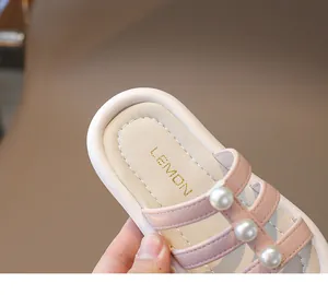Dettaglio dei cinturini in pelle rosa con grandi perle bianche sui sandali da bambina