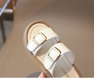Détail de sandales enfant en cuir crème avec boucles dorées et texture raffinée