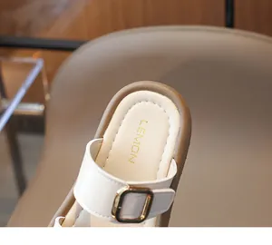 Détail de mules blanches pour filles avec boucle dorée et semelle intérieure en cuir souple