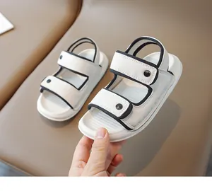 Gros plan de sandales blanches pour enfants avec bordure noire et doubles bandes velcro