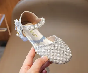 Nahaufnahme der funkelnden Perlen und Strasssteine auf silbernen Mädchen-Sandalen