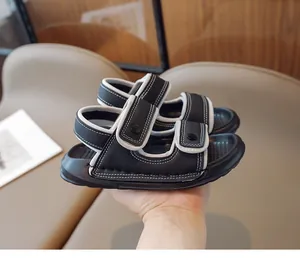 Détail de sandales noires pour enfants avec double velcro et surpiqûres blanches contrastées