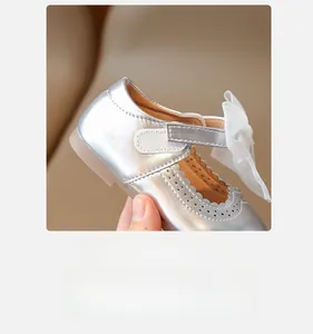 Detail of silver Mary Jane shoes with bow decoration and floral laser cutouts