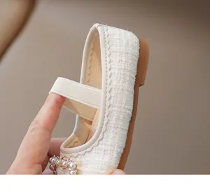 Detalle de zapato Mary Jane de tweed para niña con correa elástica y hebilla de perlas
