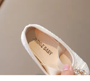 Detalle de zapato de princesa de tweed crema para niña con hebilla de perlas