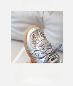 Macro shot of silver metallic children's sneaker with graffiti patterns and comfy round toe