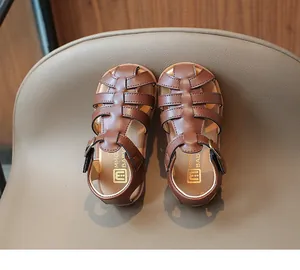Detail of retro braided brown leather kids sandals with metallic buckle and anti-slip sole