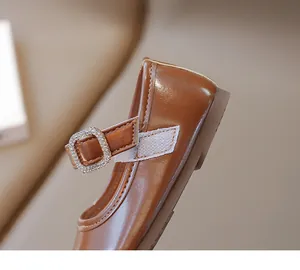 Primer plano de zapatos Mary Jane de cuero marrón para niña con hebilla de strass