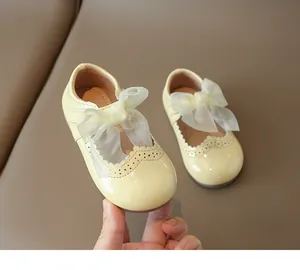 Close-up of yellow patent leather girls Mary Jane shoe with mesh bow and brogue detail