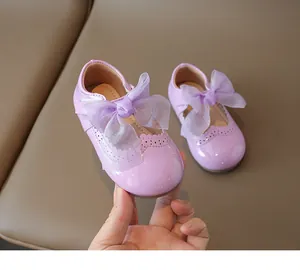 Macro detail of lavender patent leather girls shoe with translucent bow and brogue perforations