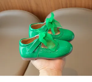 Close-up of green patent leather Mary Jane shoes with bow decoration and brogue detailing