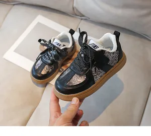 Close-up of kids retro black and white printed sneakers with glitter laces and rubber sole