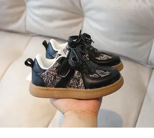 Detail of kids black sneakers with floral panels, velcro straps, and gum soles