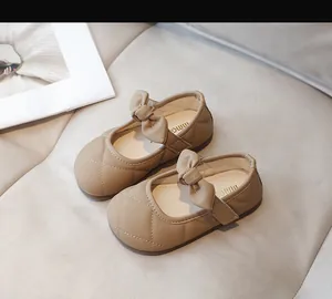 Dettaglio di scarpe Mary Jane cachi da bambina con fiocco e motivo di cucitura trapuntato