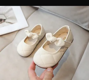 Dettaglio di scarpe Mary Jane beige per bambine con motivo trapuntato e fiocco decorativo