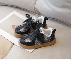 Detail of kids black leather sneakers with floral patches and durable rubber outsoles