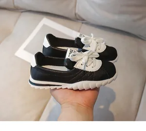 Detailed macro view of black leather upper and white wavy anti-slip sole on kids sneakers