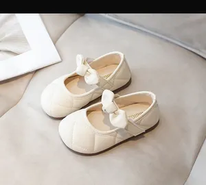 Dettaglio di scarpe Mary Jane crema con cuciture trapuntate e fiocco per bambine
