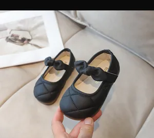 Dettaglio di scarpe Mary Jane nere trapuntate per bambina con fiocco e velcro
