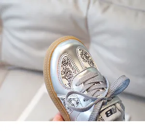 Close-up of kids sports shoe featuring silver metallic texture and floral pattern detail