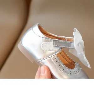 Detail of silver girls princess shoes featuring tulle bow and brogue cutout edges