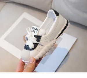 Close-up of flexible white kids sneakers with diamond stitching and big bow detail