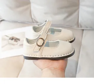 Gros plan de chaussures Mary Jane crème pour filles avec boucles bronze et semelles cousues