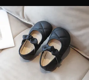 Dettaglio scarpe Mary Jane nere trapuntate per bambina con fiocco e cinturino a strappo