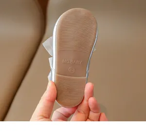Detail of silver baby girl shoes showing the non-slip rubber sole and bow decoration