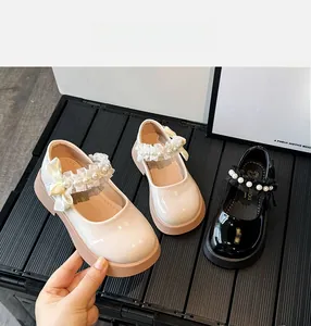 Detail of girls' patent leather Mary Janes with silk bows and pearl lace straps