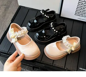 Detail of glossy patent leather Mary Jane shoes with pearl bows and thick rubber soles