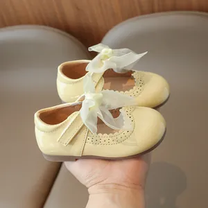 Yellow patent leather girl's Mary Jane shoes with mesh bow and scalloped trim details