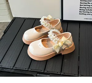 Detail of cream Mary Jane shoes featuring lace pearls and satin bow on striped board
