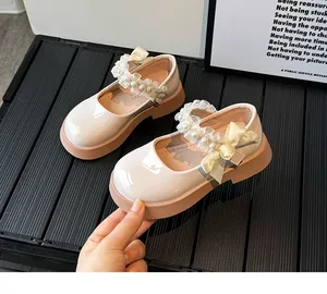 Detail of girls' cream Mary Janes featuring pearl strap and yellow bow decoration