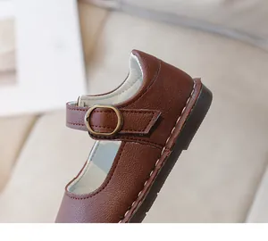 Détail de Mary Janes en cuir marron foncé avec boucle rétro et surpiqûres blanches