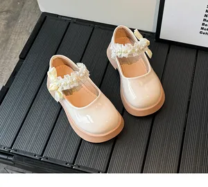 Detail of girls' cream Mary Janes with lace pearls and yellow silk bow accents